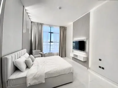 a white bedroom with a bed and a television at Al Manara Premium Lux Studio in Dubai
