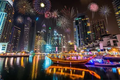 a boat in the water with fireworks in a city at Barsana - Seaside Luxury 2BDR - Panoramic Marina & Sea Views in Dubai