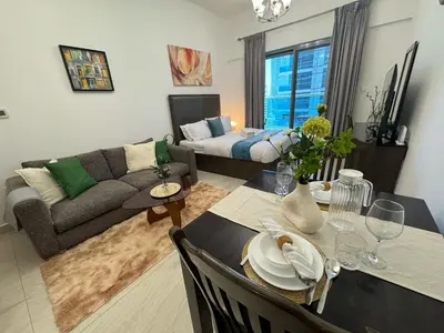 a living room with a couch and a dining table at Chic Studio with Balcony a mins drive to Downtown in Dubai