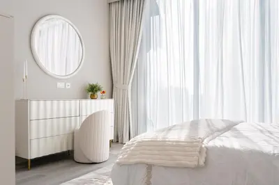 a white bedroom with a bed and a mirror at 1 Bedroom Marina with Canal View in Dubai