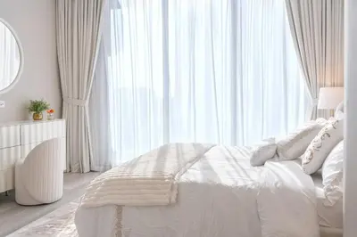 a white bedroom with a bed and a large window at 1 Bedroom Marina with Canal View in Dubai