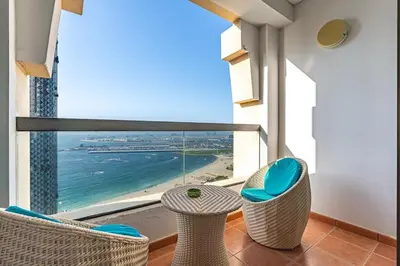 a balcony with chairs and a view of the ocean at Bright and Spacious 2BR with Pool and Gym Access in Dubai