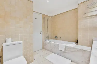 a bathroom with a tub and a toilet and a sink at Bright and Spacious 2BR with Pool and Gym Access in Dubai