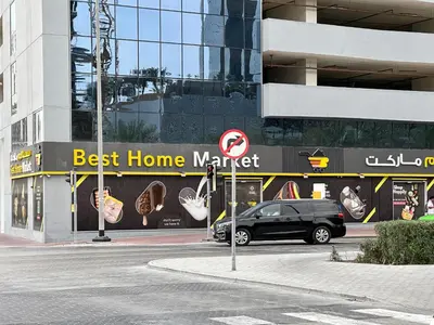 a black car parked in front of a best home market at Trophy-Brandnew Premium and Vibrant 1BR in JVC in Dubai