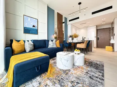 a living room with a blue couch and a table at Trophy-Brandnew Premium and Vibrant 1BR in JVC in Dubai