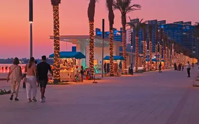 a group of people walking down a boardwalk with christmas lights at Elegant 1-BR with Sea View Seven Palm, Palm Jumeirah in Dubai