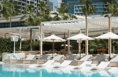 a swimming pool with white chairs and umbrellas at Elegant 1-BR with Sea View Seven Palm, Palm Jumeirah in Dubai