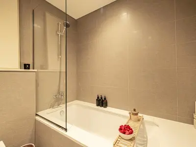 a bathroom with a tub and a glass shower at Burj Royale Suites by Prestige Nest in Dubai