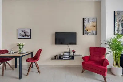 a living room with red chairs and a table and a tv at Luxury new studio Dubai Marina 10min to the beach in Dubai