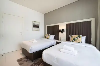 a hotel room with two beds with white sheets at Bay's Edge, Luxury Canal View 2BR in Business Bay in Dubai