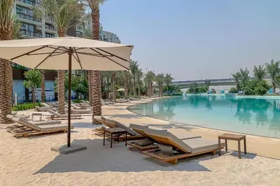 a swimming pool with lounge chairs and an umbrella at Spacious 3BR, Private Beach Access in Dubai