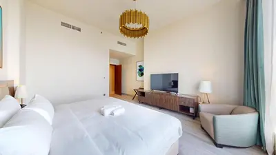 a bedroom with a white bed and a couch and a television at Locations I Avani Palm View I Luxury 2 Bedroom I Sea View I Pool, Gym, Parking, Wi-Fi in Dubai