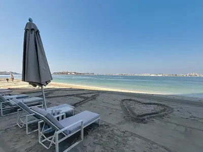 a group of lounge chairs and an umbrella on a beach at Grand Bleu - Luxurious One Bedroom with Sea View in Dubai