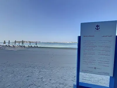 a sign on a beach with the ocean in the background at Grand Bleu - Luxurious One Bedroom with Sea View in Dubai