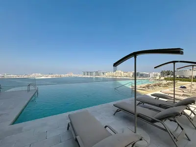 a swimming pool with lounge chairs next to the water at Grand Bleu - Luxurious One Bedroom with Sea View in Dubai