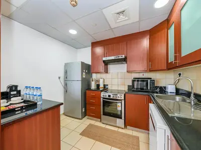 a kitchen with wooden cabinets and stainless steel appliances at Palm & Sea View Beach Acess JBR walk Skydive clubs in Dubai