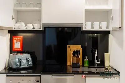 a kitchen with white cabinets and a black counter top at The Chic in Dubai