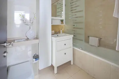 a white bathroom with a sink and a shower at Frank Porter - Botanica Tower in Dubai