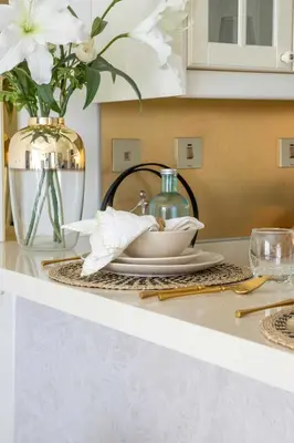 a kitchen counter with a plate and a vase with flowers at Frank Porter - Botanica Tower in Dubai