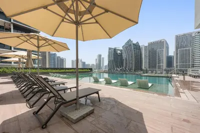 a group of chairs and tables with umbrellas on a building at Silkhaus Highfloor 1BDR in 15 Northside Tower in Dubai