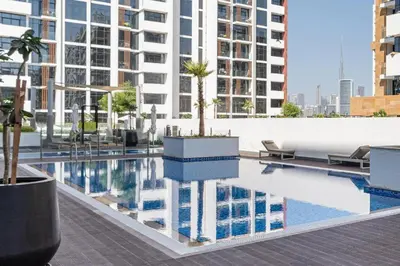 a pool with a palm tree on top of a building at Fully Furnished Modern Studio Apartment Nearby Meydan Racecourse in Dubai