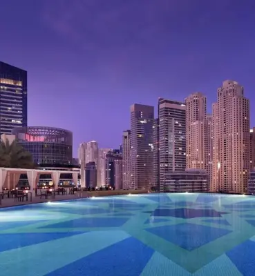 a large swimming pool with a city skyline at night at Cosmos Living Studio at JW Marina in Dubai