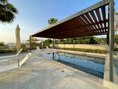 a pool with a wooden umbrella and chairs and a swimming pool at GuestReady - Panoramic views from One JBR in Dubai
