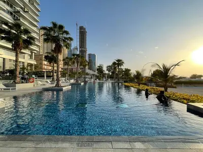 a large swimming pool with palm trees in a city at GuestReady - Panoramic views from One JBR in Dubai