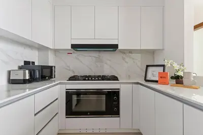 a kitchen with white cabinets and a black appliance at GuestReady - Modern retreat in JVC in Dubai