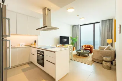 a kitchen with white cabinets and a living room at High-Floor Luxury 2BR, Sea View, Address JBR in Dubai