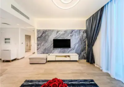 a living room with a couch and a tv on a wall at Modern one bedroom apartment in lotus creek beach in Dubai