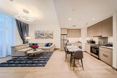 a kitchen and living room with a couch and a table at Modern one bedroom apartment in lotus creek beach in Dubai
