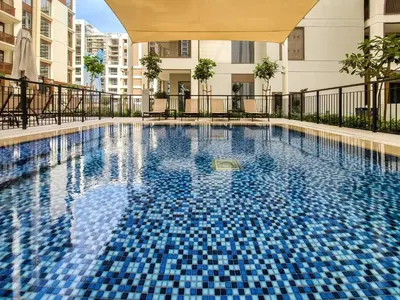 a swimming pool with blue tiles in a building at Modern one bedroom apartment in lotus creek beach in Dubai