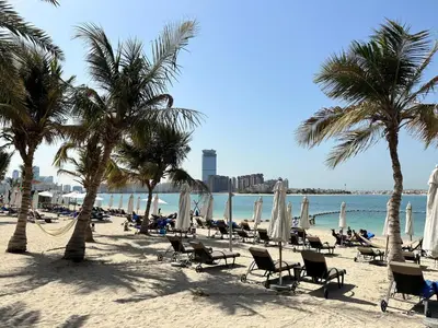 a beach with chairs and palm trees and the ocean at Dream Palm Residence 3BR Luxury Apartment on Palm Jumeirah in Dubai
