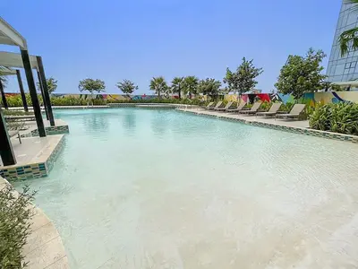 a large swimming pool with chairs in the water at FIRST CLASS 1BR Luxe Comfort Stylish Design in Dubai