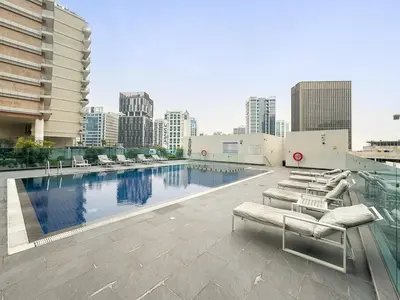a pool on the roof of a building with lounge chairs at FIRST CLASS Studio Cozy Luxe Sanctuary in Dubai