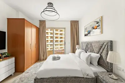a bedroom with a white bed and a television at FIRST CLASS Studio Cozy & Chic Retreat in Dubai