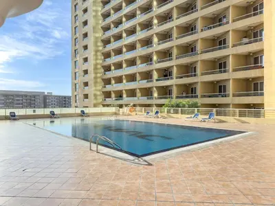 a swimming pool in front of a large building at FIRST CLASS Studio Cozy & Chic Retreat in Dubai