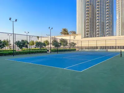 a tennis court in front of a large building at Spacious Dubai Apartment with Water Views and Luxury Amenities in Dubai