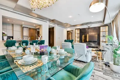 a dining room with a glass table and green chairs at Highend 2BR Palm Sea View with Pool and Nightlife Marina in Dubai