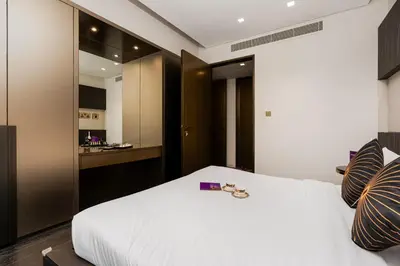 a bedroom with a white bed and a kitchen at Highend 2BR Palm Sea View with Pool and Nightlife Marina in Dubai