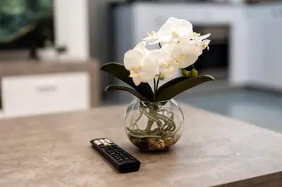 a vase with white flowers sitting next to a remote control at Dubai Marina - 1 BHK Stunning Apartment in Dubai