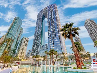 a tall building with a palm tree in front of it at PRIVACASA - The Address Beach Resort residences in Dubai