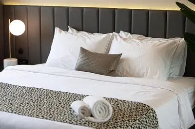 a bed with white sheets and towels on it at 2BR Dubai Gem steps from Dubai Mall & Burj in Dubai