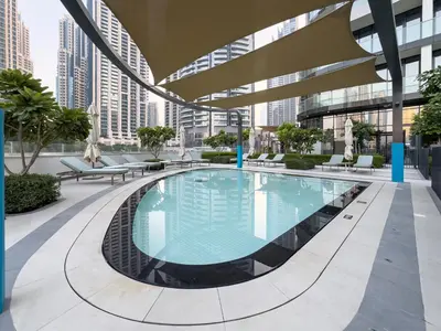 a large swimming pool in a building with tall buildings at Elegant 1BR I 1min walk to Burj Khalifa & Fountain in Dubai