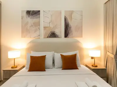 a bedroom with a white bed with three paintings on the wall at EMAAR GRANDE 1BR Downtown I Steps to Fountain & Dubai Mall in Dubai