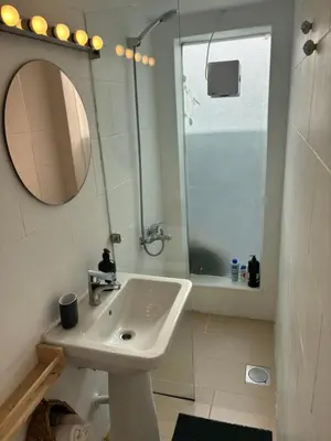 a white bathroom with a sink and a mirror at Private Cottage with bbq area 5 min walk to beach! in Dubai