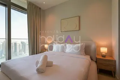 a bedroom with a large white bed with a window at Spacious and Elegant 2BR Marina Gate 2 in Dubai