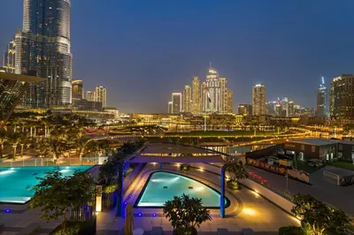 a view of a city at night with a pool at Panoramic 2BR with Pool & Burj View Next to Mall in Dubai