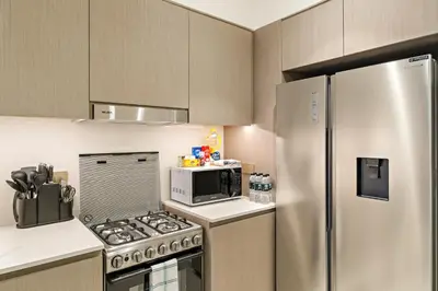 a kitchen with a stainless steel refrigerator and a microwave at Panoramic 2BR with Pool & Burj View Next to Mall in Dubai
